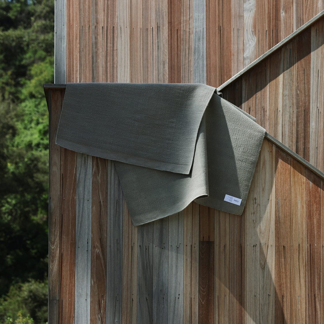 Fable Slate Gray rug draped over a wooden railing with a natural background #slategray