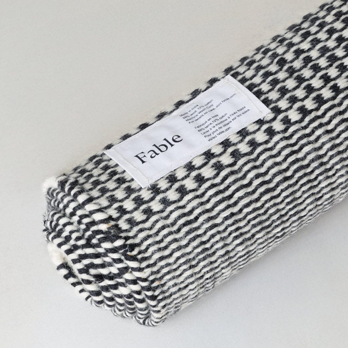 Folded black and white patterned fabric with 'Fable' label on a light gray background #ashblack