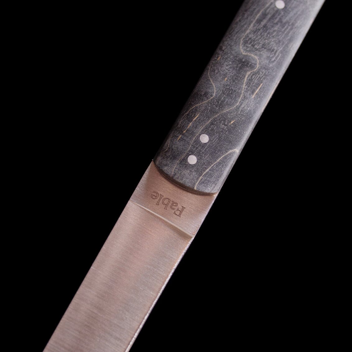 Close-up of a knife blade with 'Rapee' branding on a black background