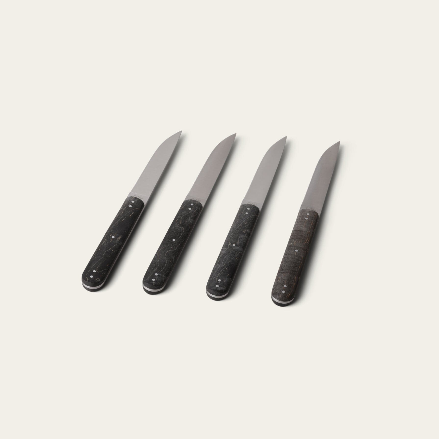 Four black-handled knives on a light gray background